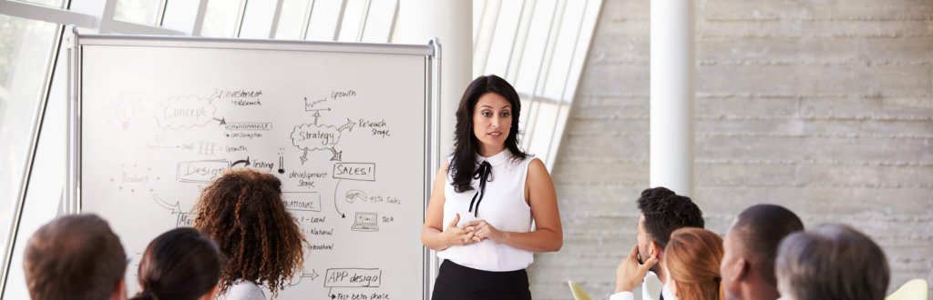 Hispanic Businesswoman Leading Meeting At Boardroom Table